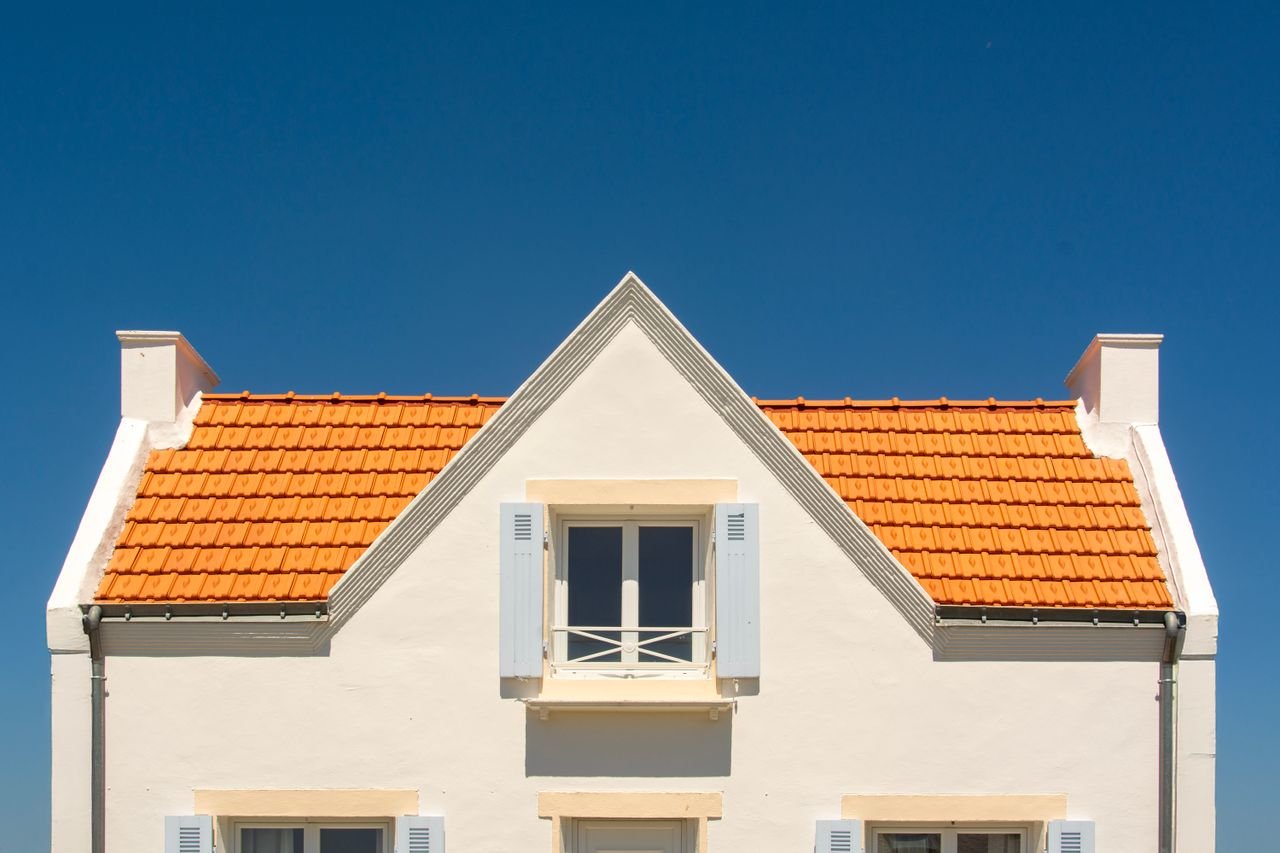 Home Front view of a house with orange tile roof and blue sky background.